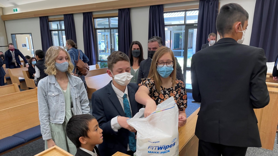 Members of The Church of Jesus Christ of Latter-day Saints in Nambour, Australia collect disinfecting wipes so they can prepare their chapel before a second congregation arrives to worship. 18 July 2021.