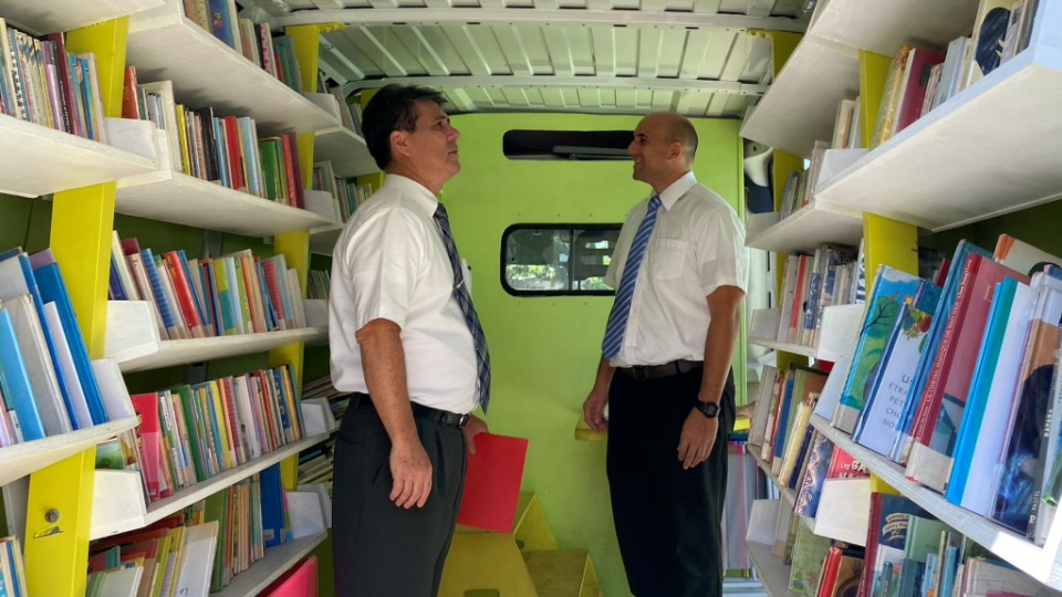 Church-leaders,-Elder-Frederic-Riemer,-Area-Seventy,-and-Manea-Tuahu,-welfare-and-self-reliance-services-look-inside-the-library-mobile-unit-on-the-island-of-Moorea,-French-Polynesia.