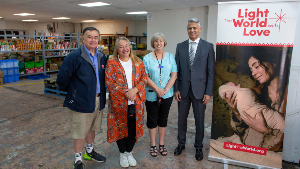 Elder-Glenn-Burgess-(right)-is-joined-by-Salvation-Army-Community-Centre-Manager-Kerri-Palma-and-her-staff-in-the-food-distribution-area-during-a-visit-to-present-a-'Light-the-World-with-Love'-donation.-New-Zealand,-December-2021.