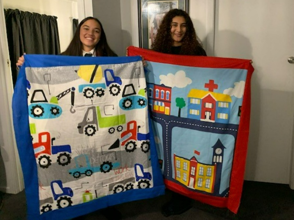 Volunteers show the quilts they made.